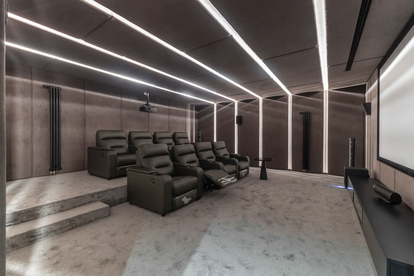 Private cinema room with suede-upholstered walls and ceiling, linear LED lighting and two rows of recliners