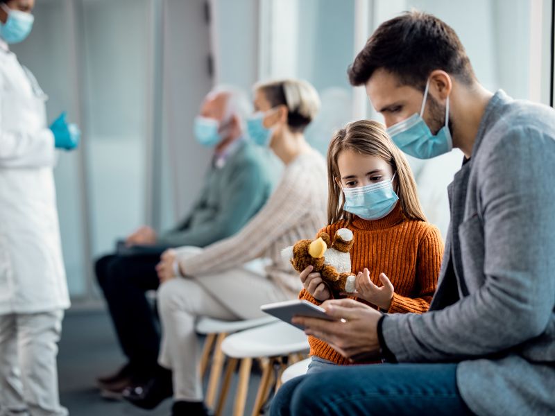 Doctor's office interior, father in need of non-profit medical bill assistance