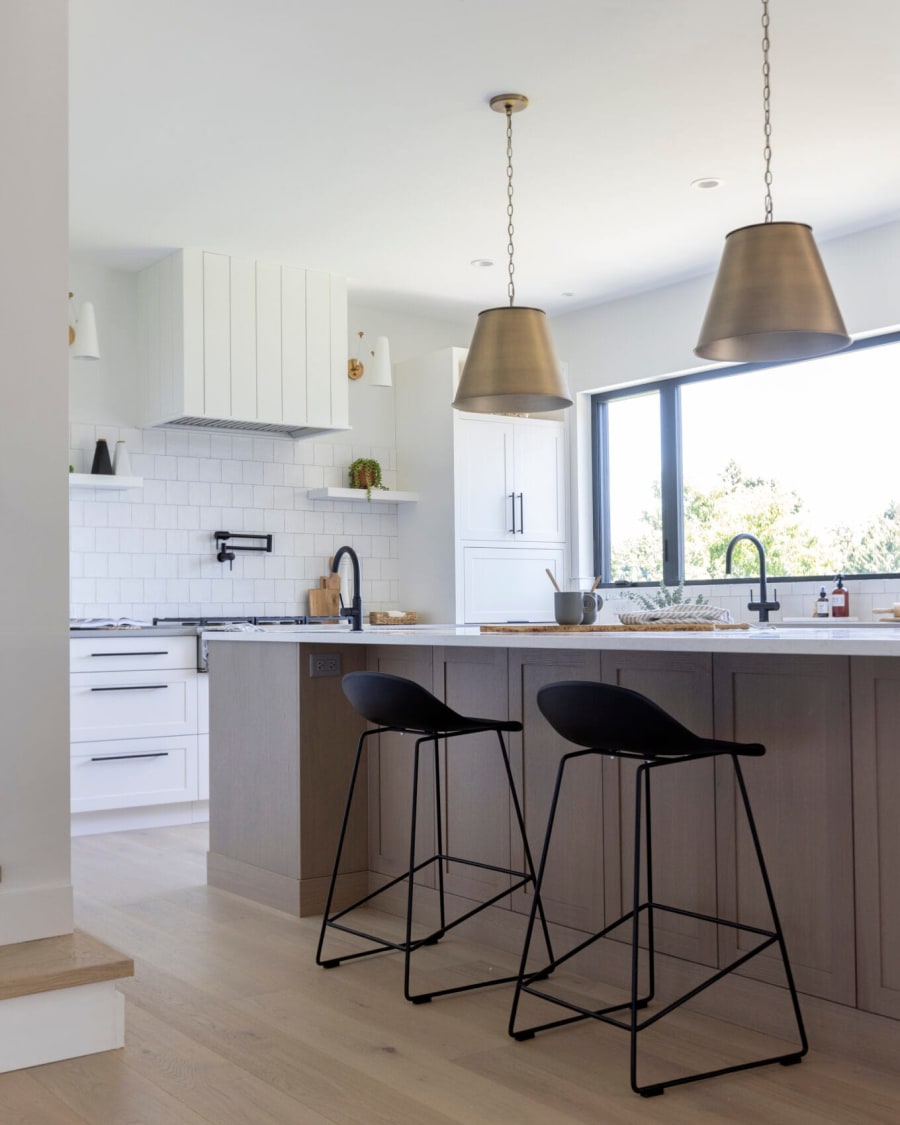 Light kitchen with oak cabinetry and brass pendants