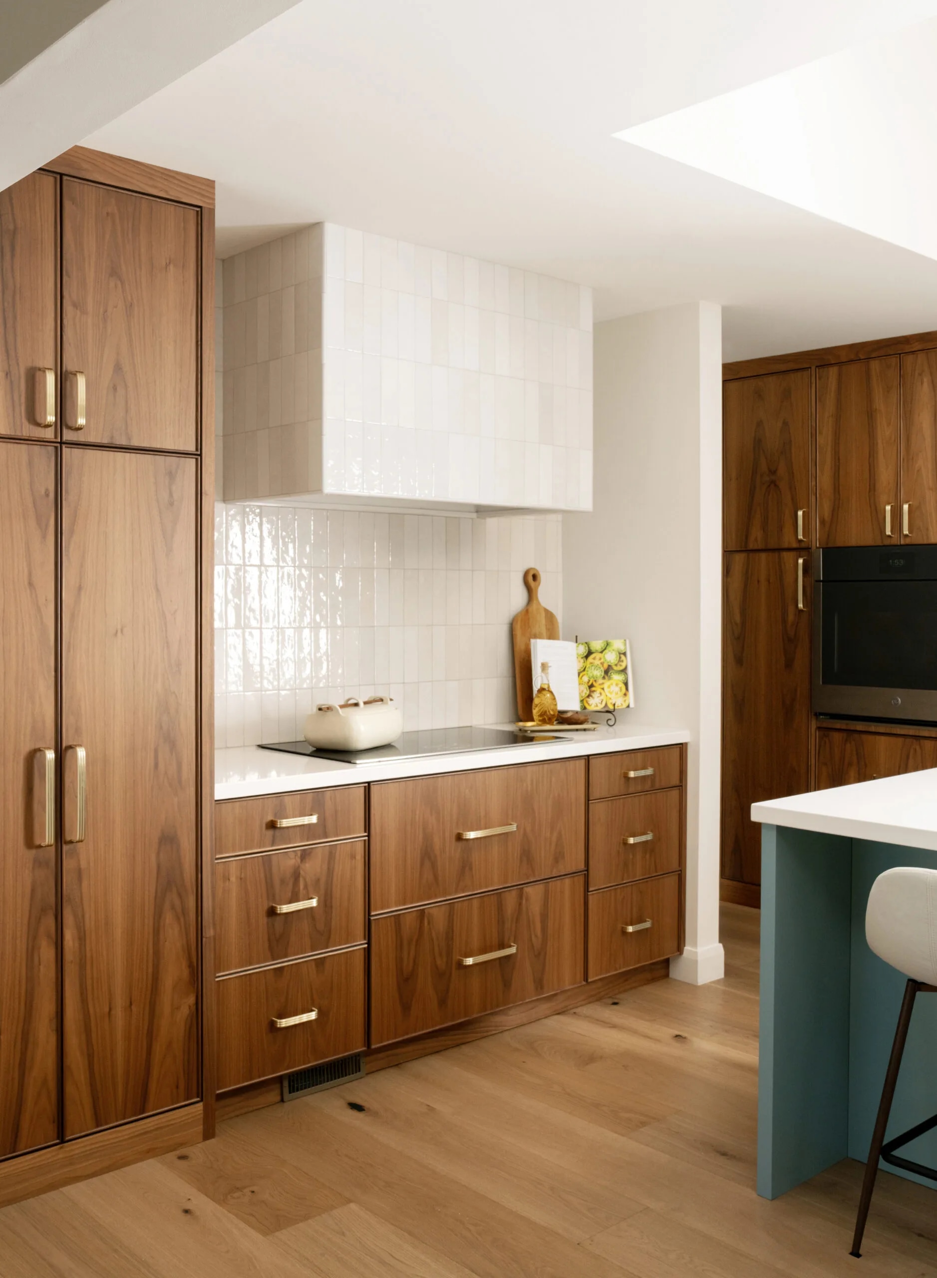 Walnut cabinetry with brass hardware and tiled hood