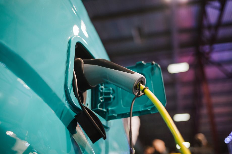 Blue electric van being recharged with a plug in cable.