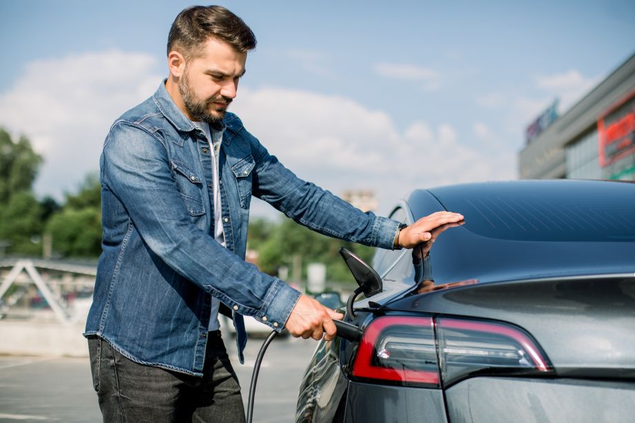 Driver charging up an electric car at a charging point