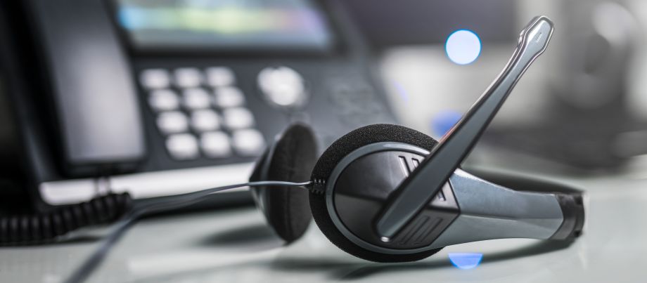 Headset next to a VoIP office phone on a desk