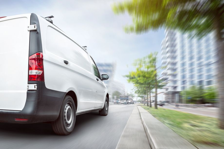 A 5-seater van driving through a city area doing a delivery