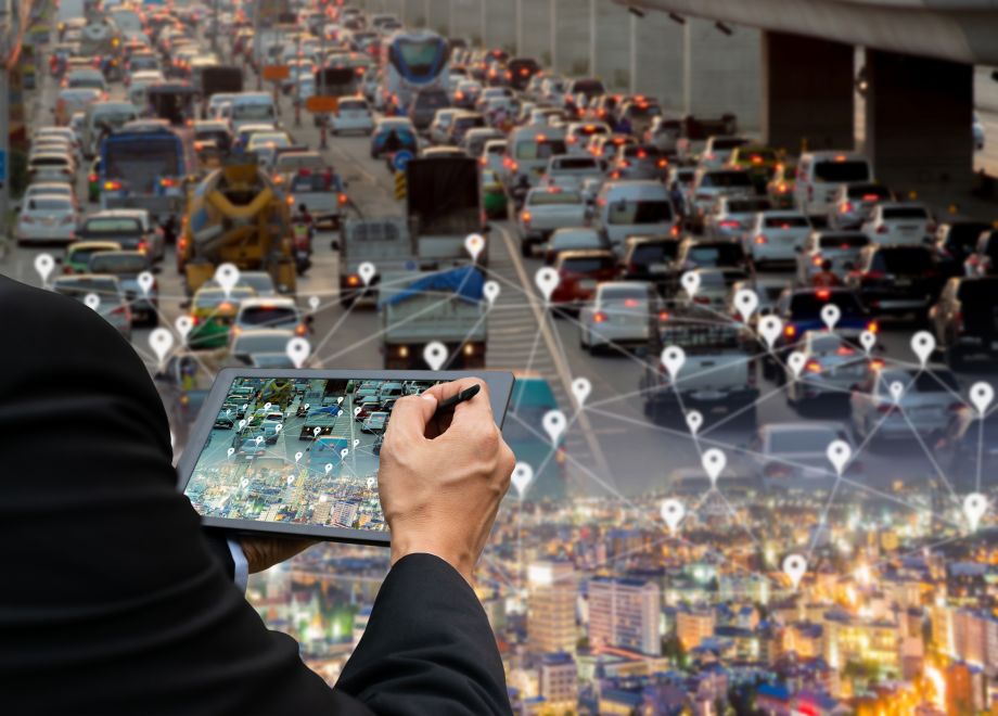 Person holding an iPad using a GPS tracking system to see location of cars on the road