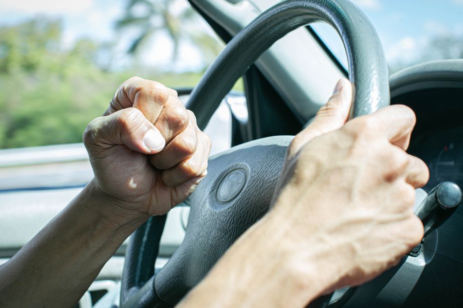 Driver honking car horn in road rage while clenching fist