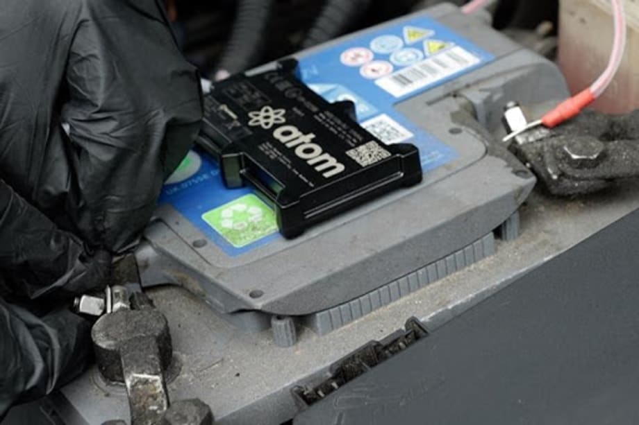 Telematics device on a vehicle battery being installed by a driver 