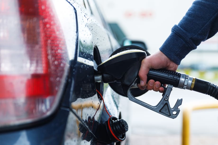 Employee refilling a work vehicle car with fuel at a pump station