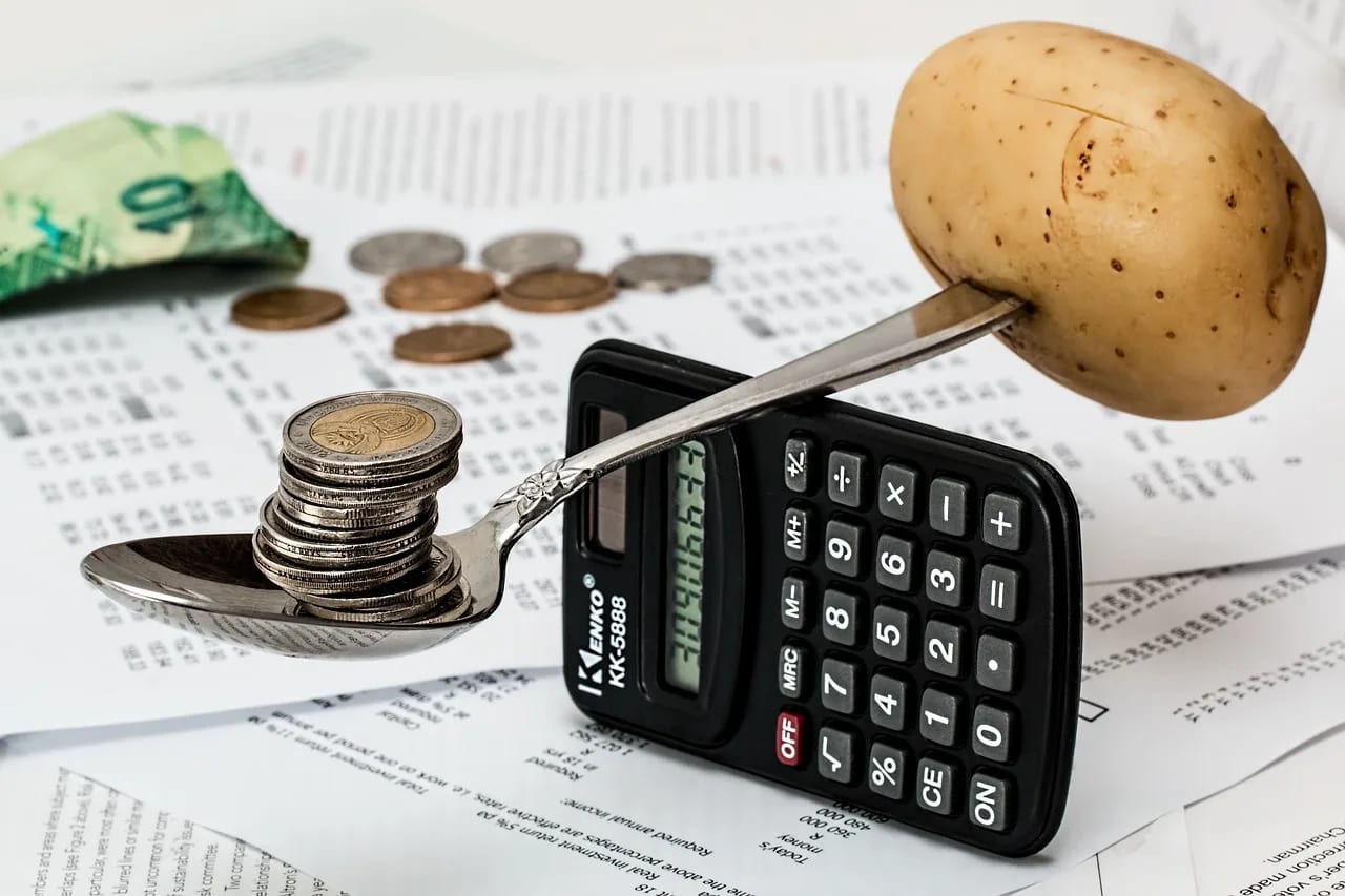 Monedas de euro, una calculadora financiera y un bolígrafo sobre documentos impresos con presupuestos