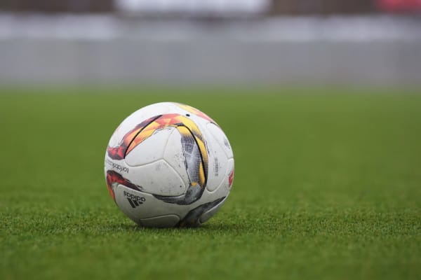Un balón de fútbol clásico sobre el césped verde de un campo de juego.