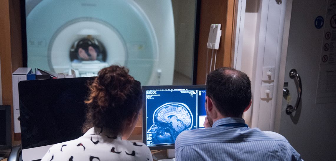 Two researchers in MRI scanner control room looking at an image on the monitor