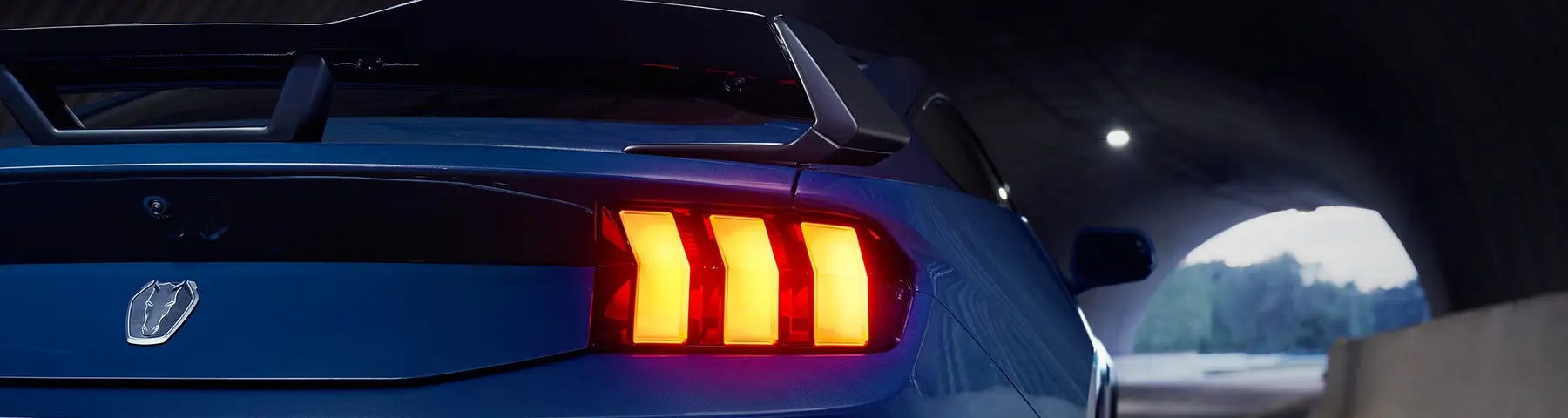 Rear of a blue Ford Mustang Dark Horse with the horse-head trunk badge above the left taillight