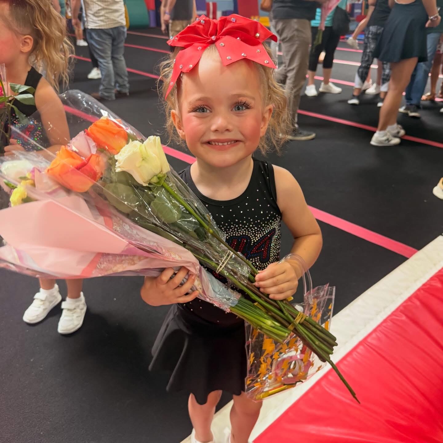 Young Tier 1 cheerleader with a red bow holding a bouquet of roses