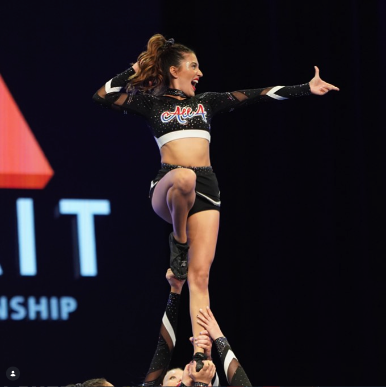 All 4 cheerleader held up in a stunt by her teammates.
