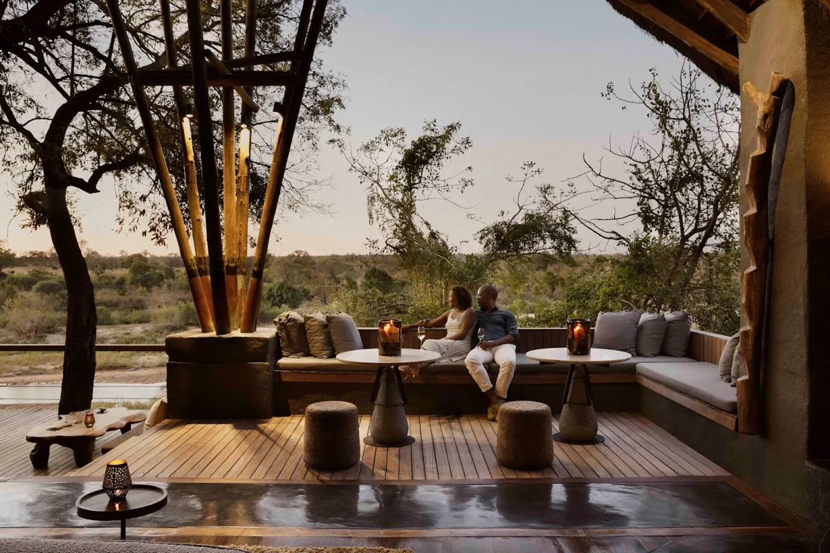 Guests on the open deck at Singita Boulders Lodge overlooking the Sand River in the Sabi Sand