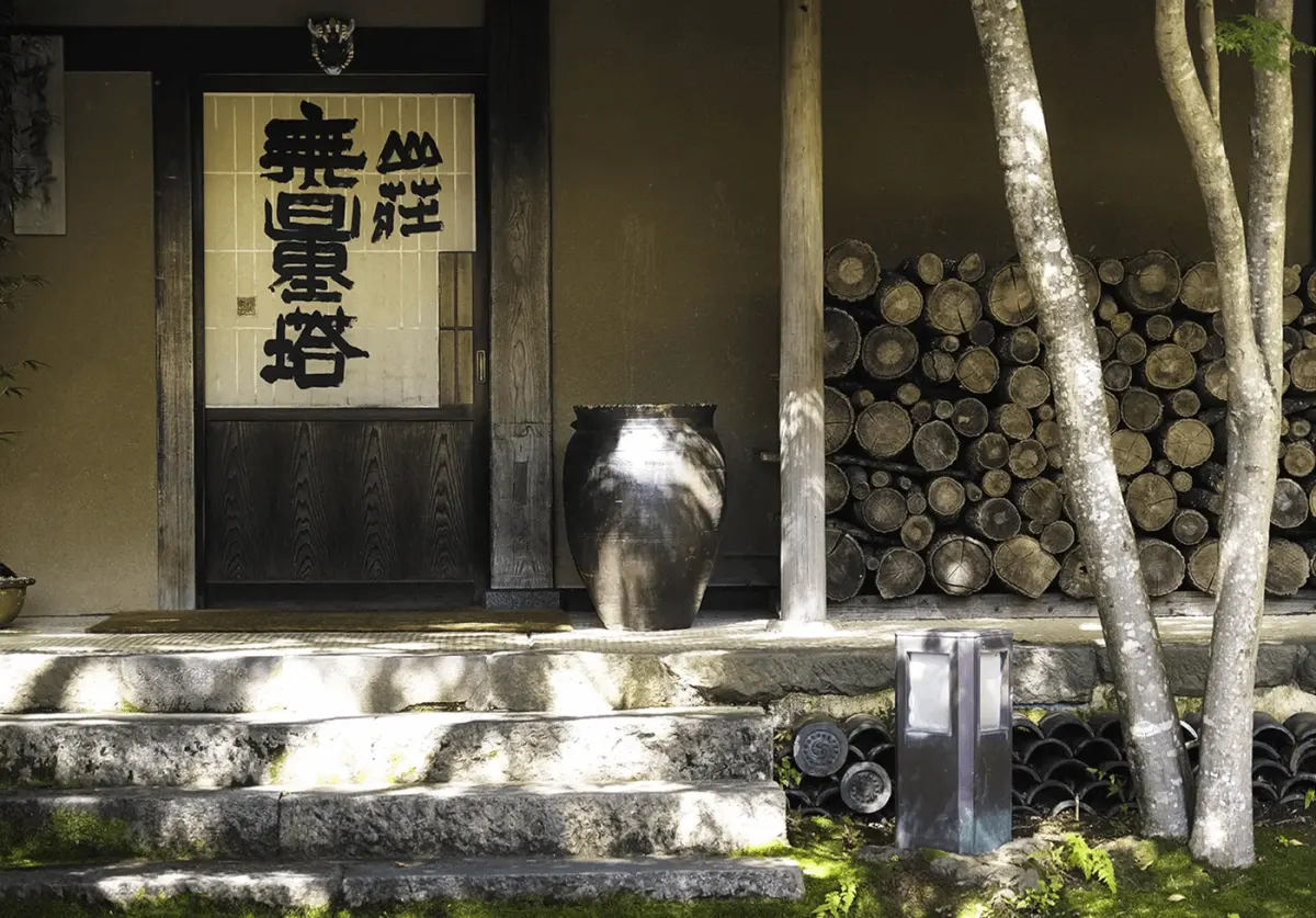 Sansou Murata Yufuin traditional entrance with noren curtain and woodpile — luxury onsen ryokan Kyushu