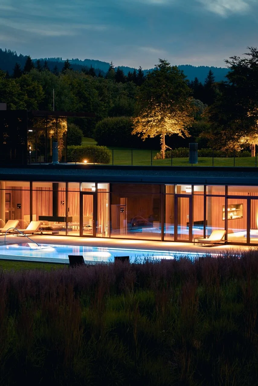 Illuminated pool at Lanserhof Tegernsee medical spa on Lake Tegernsee in Bavaria at dusk