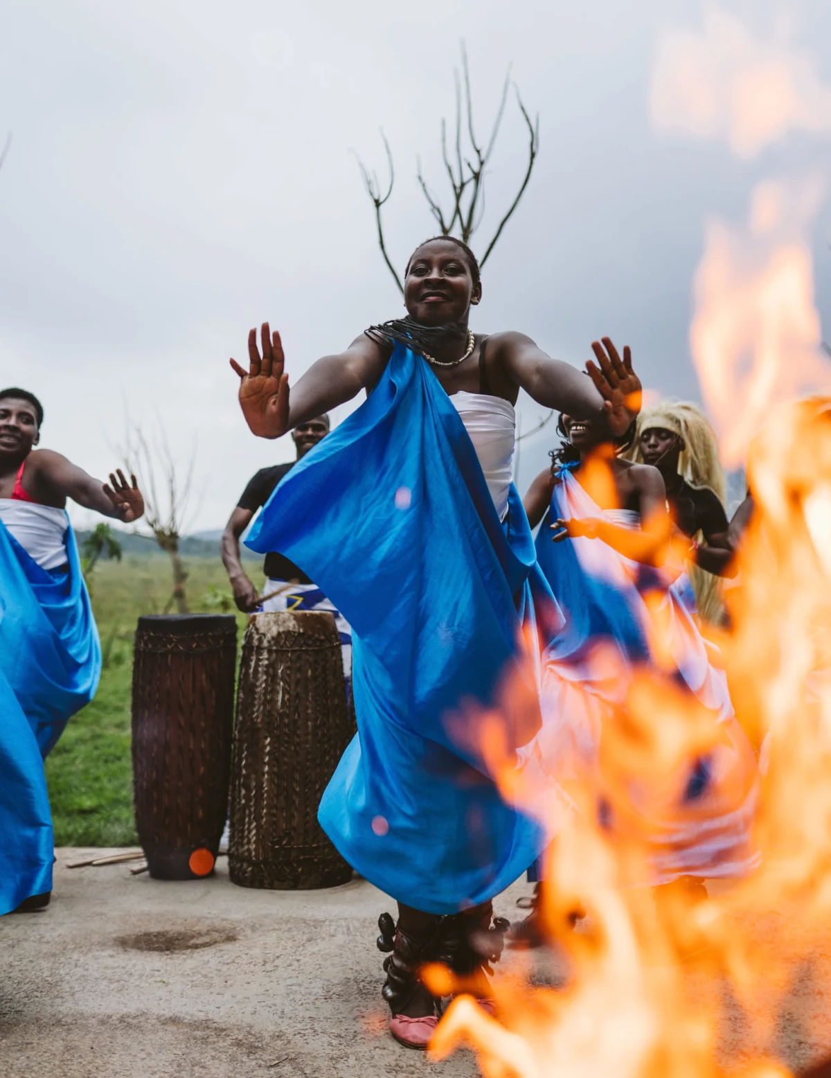 Women in bright blue traditional dress dancing around a fire at Singita in Rwanda
