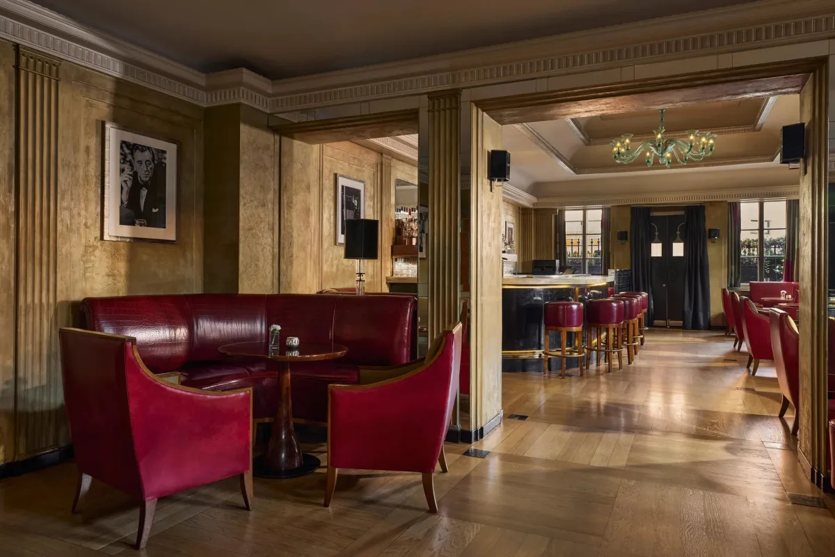 The Art Deco Claridge's Bar in Mayfair with red leather banquettes, gold walls and a green glass chandelier