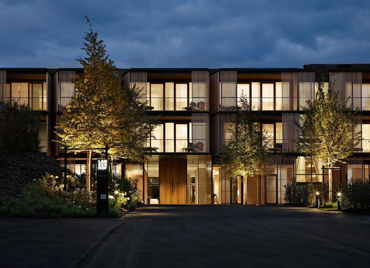 The larch-clad Lanserhof Tegernsee building lit at dusk in the Bavarian foothills, Germany