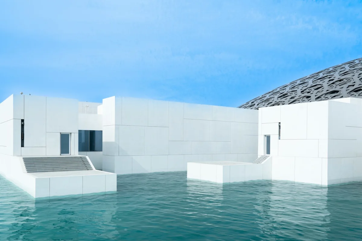 The white cubic pavilions and perforated dome of the Louvre Abu Dhabi rising from the water