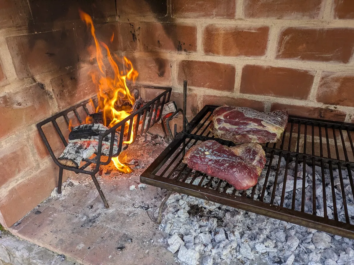 Beef cooking slowly over a wood fire on a brick parrilla, Argentina