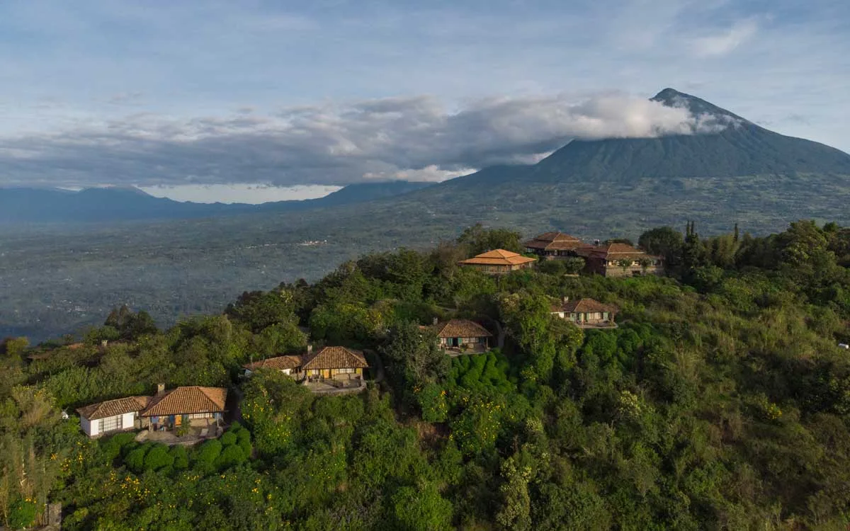 Aerial view of the hilltop bandas at Virunga Lodge in Rwanda with a Virunga volcano rising behind