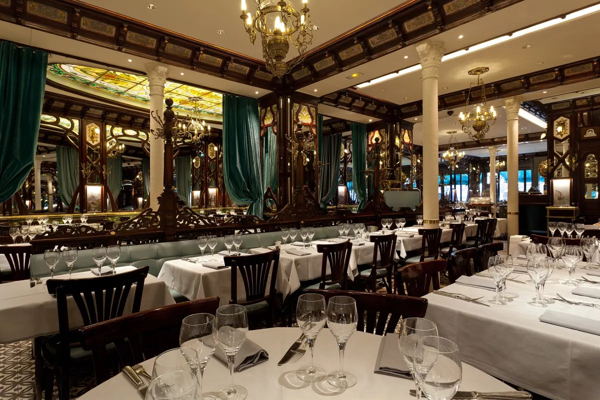 Belle Epoque dining room of a historic Paris brasserie with stained glass, mirrors and white linen