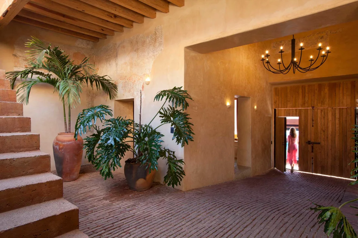 The restored casona entrance hall of Escondido Oaxaca hotel with frescoed walls and brick floors