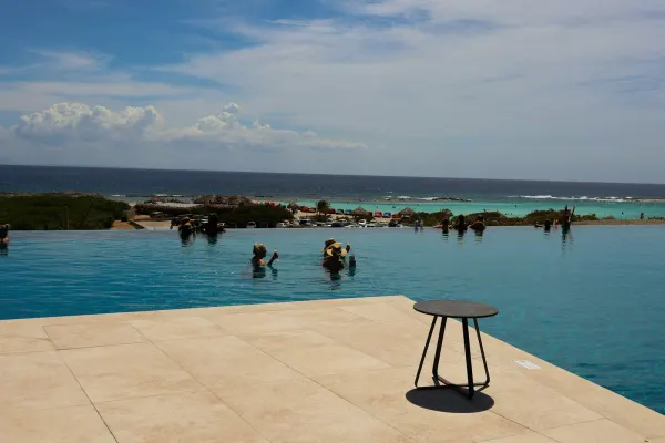 A family swims in an infinity pool overlooking the ocean at a multigenerational luxury resort