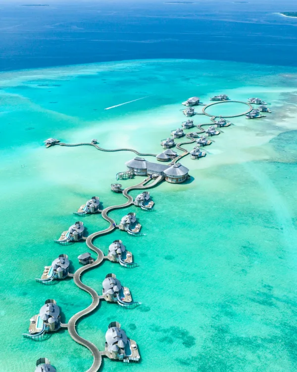 Aerial of overwater villas above a turquoise Maldives lagoon, the classic Indian Ocean honeymoon