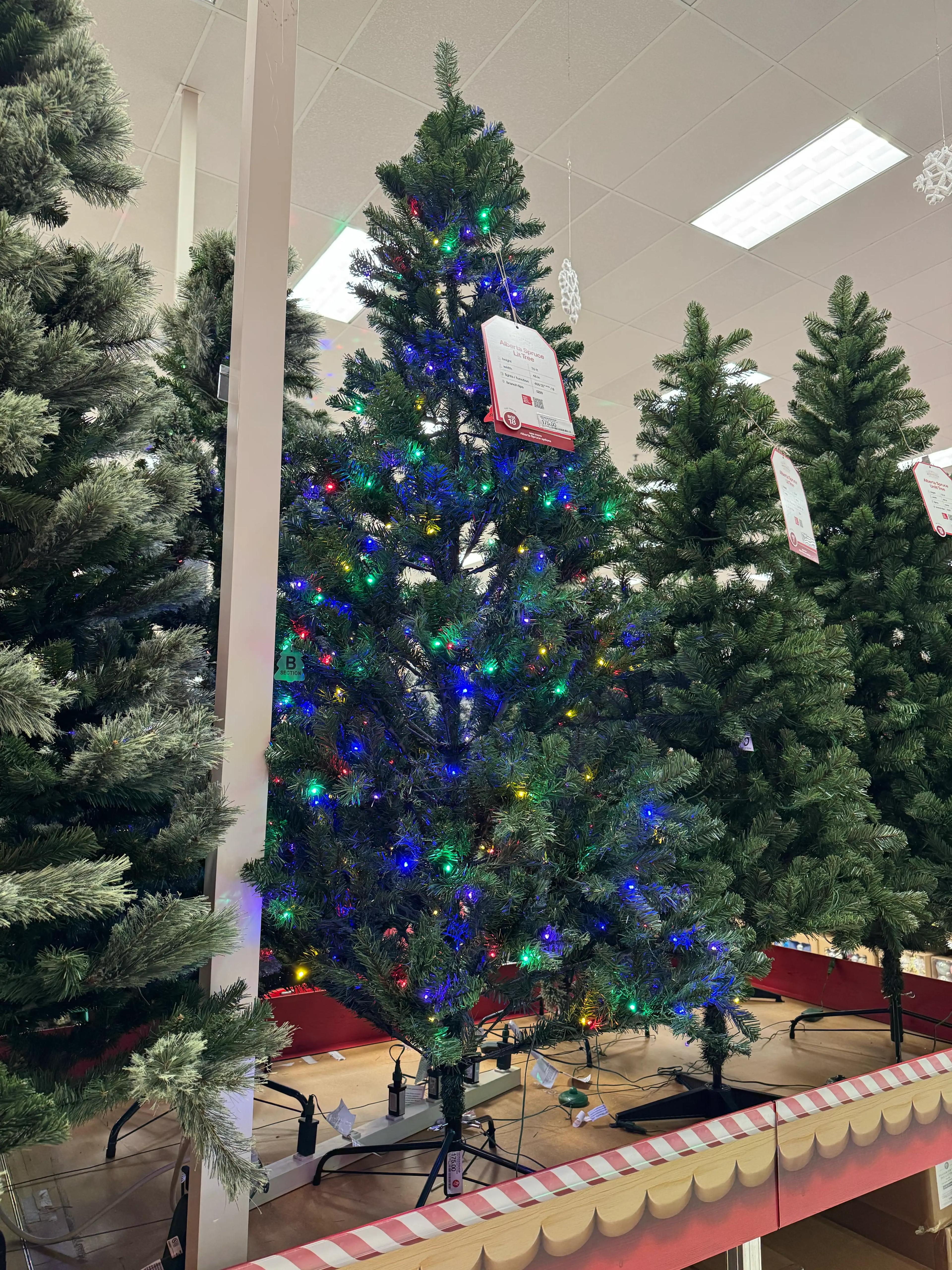 Traditional PVC spruce with moderate branching, visible gaps, multicolor mini bulbs densely distributed throughout