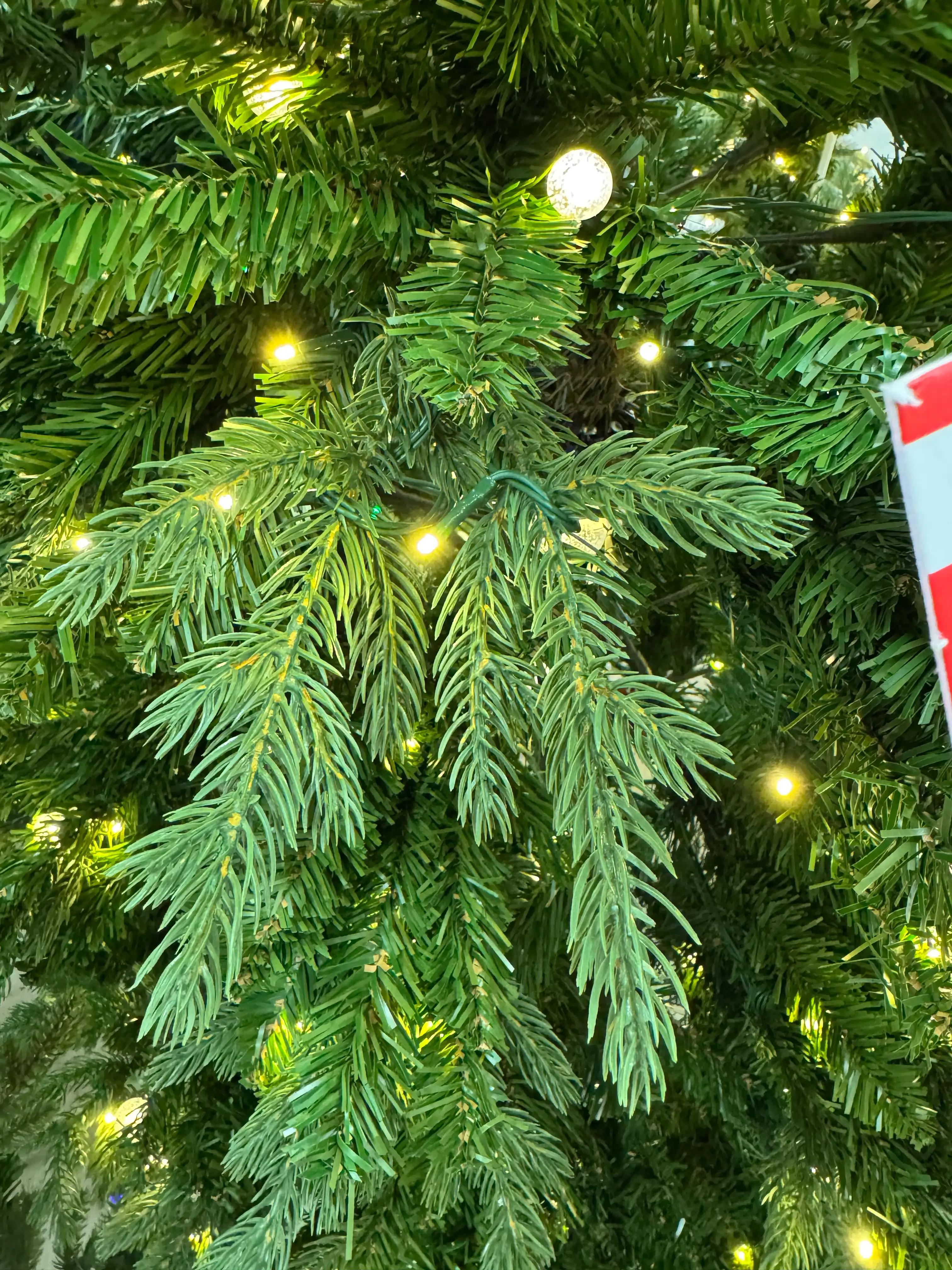 Mixed PVC and PE spruce needles, warm white LED lights scattered throughout, moderate density with some visible gaps