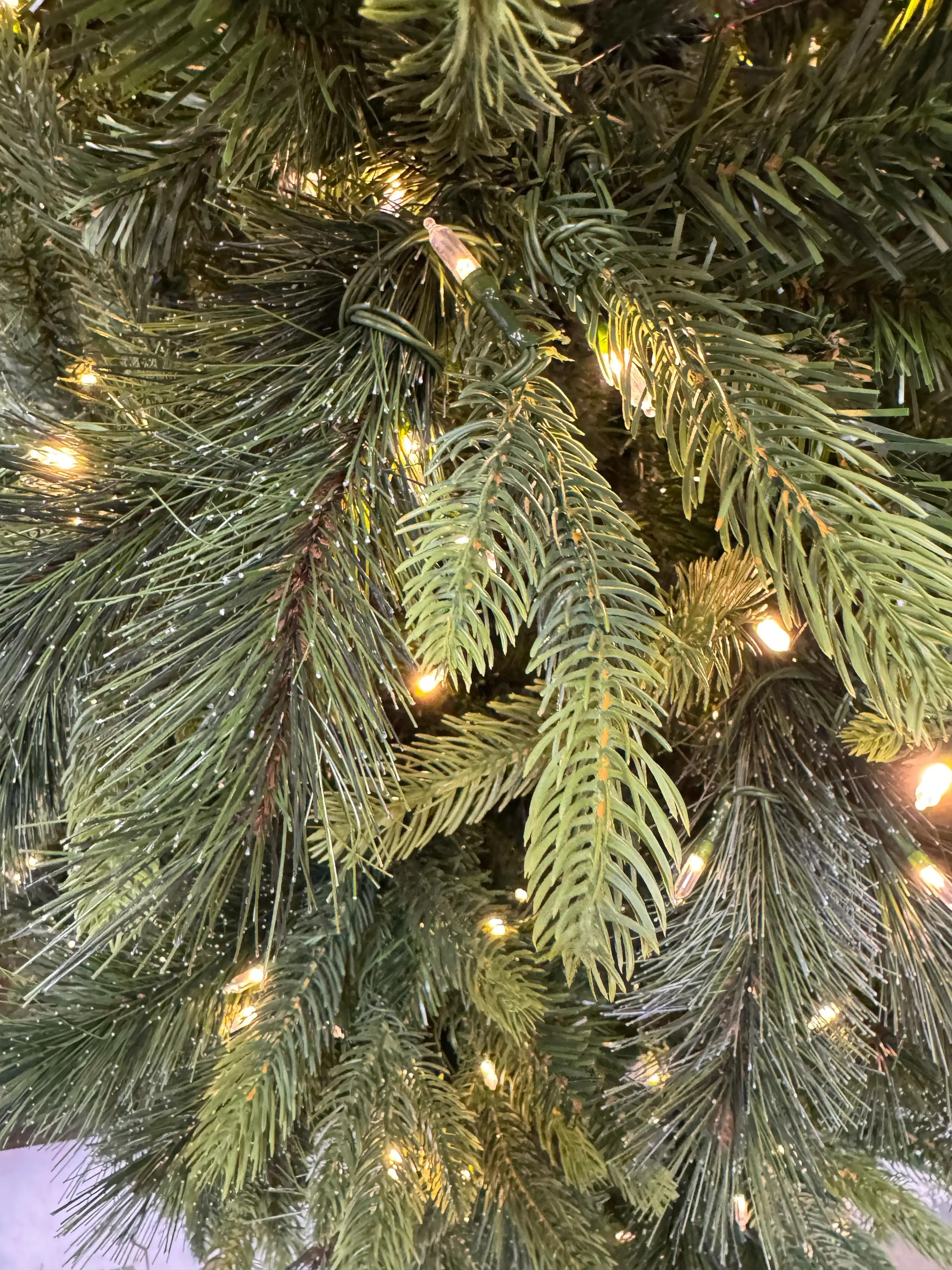 Dense PVC pine needle clusters in varied green tones, warm white mini LED lights evenly distributed throughout branches