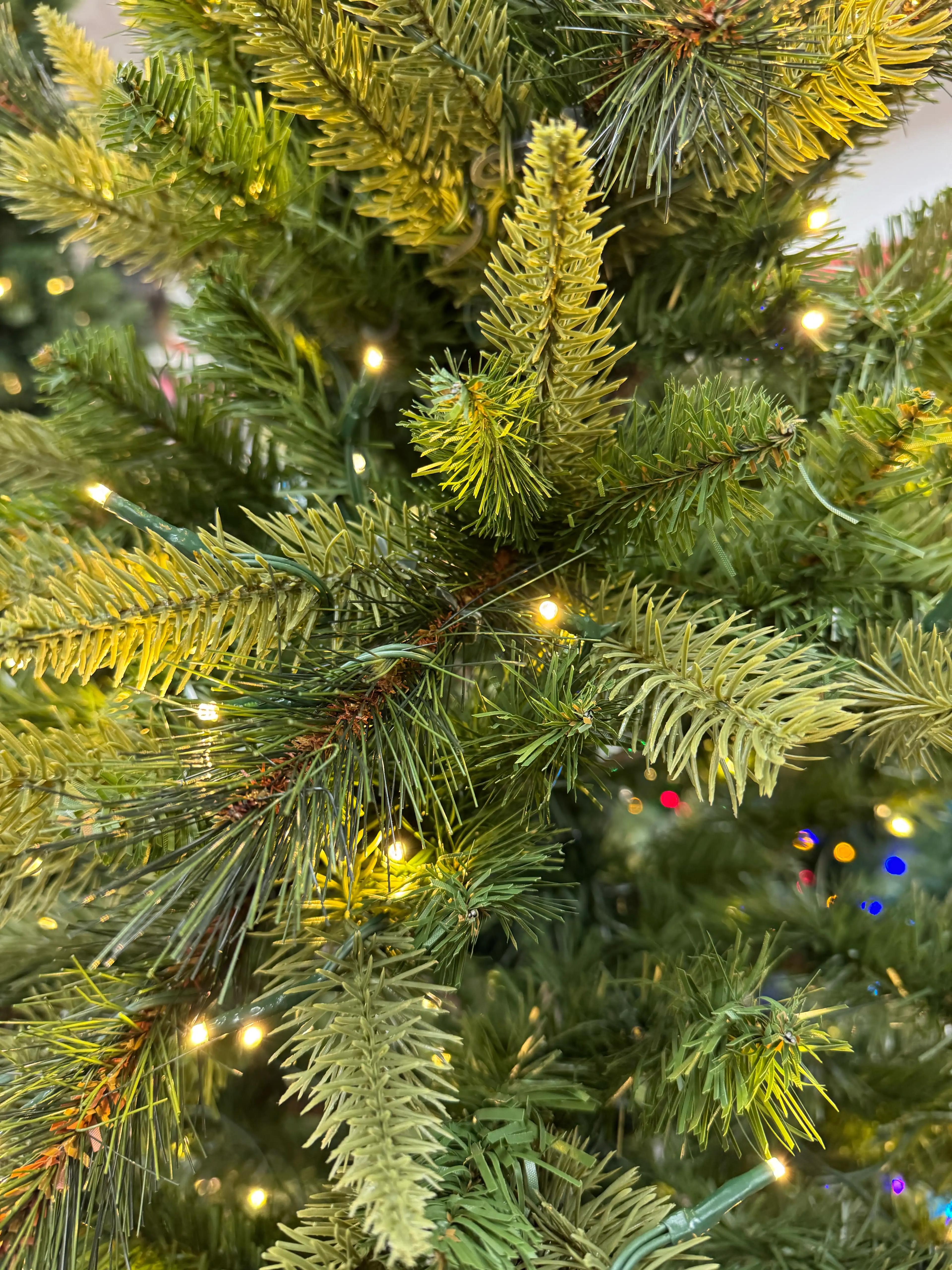 Mixed PVC and molded PE spruce needles in green/yellow tones, warm white micro LEDs, moderate density with some gaps