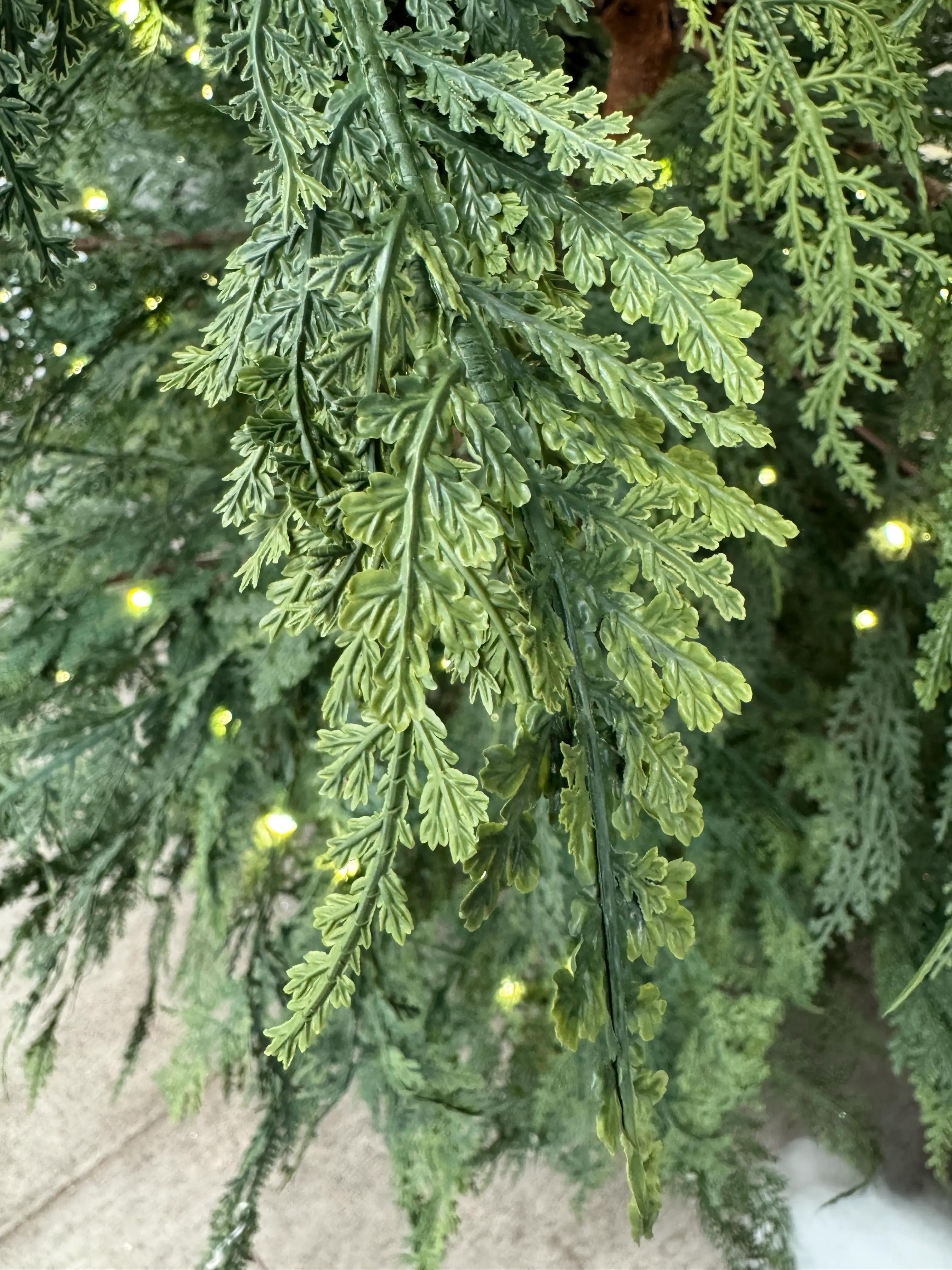 Close-up of realistic molded PE cypress-style foliage with flat, scale-like green needles in layered sprays