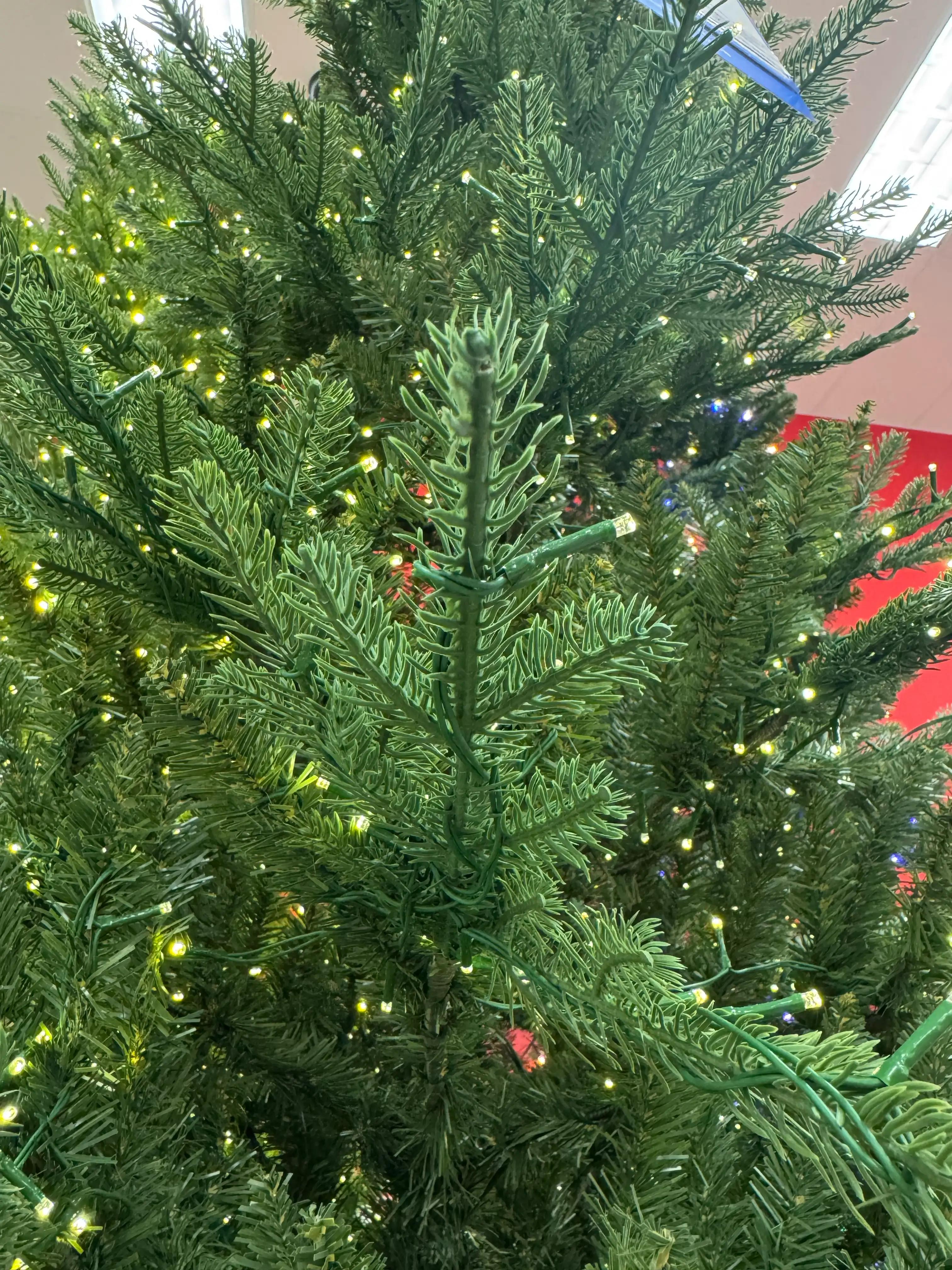 Close-up of dense PVC spruce needles in mixed green tones, warm white micro LEDs throughout, minimal visible gaps