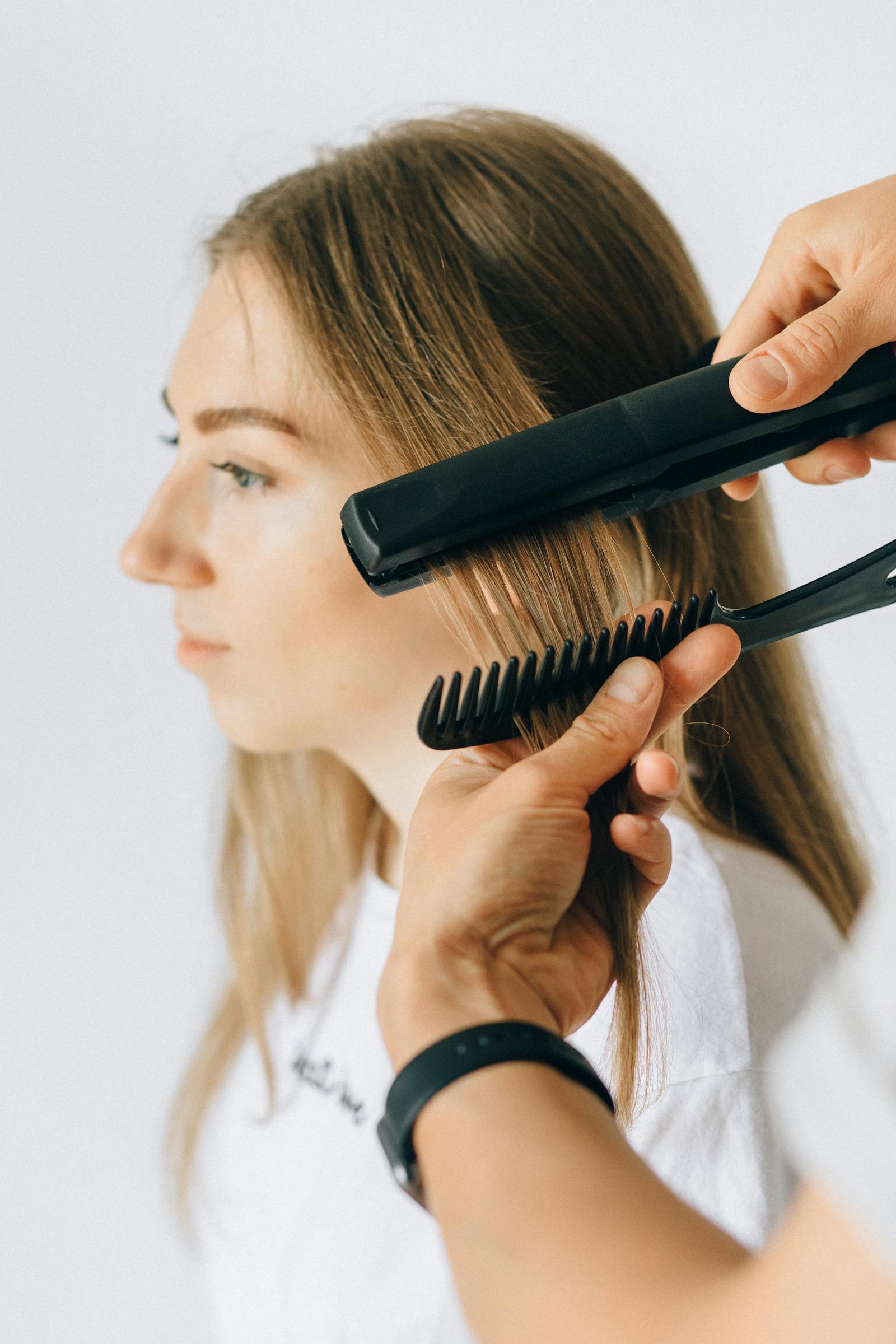 Stylist using a flat iron to smooth a client's hair