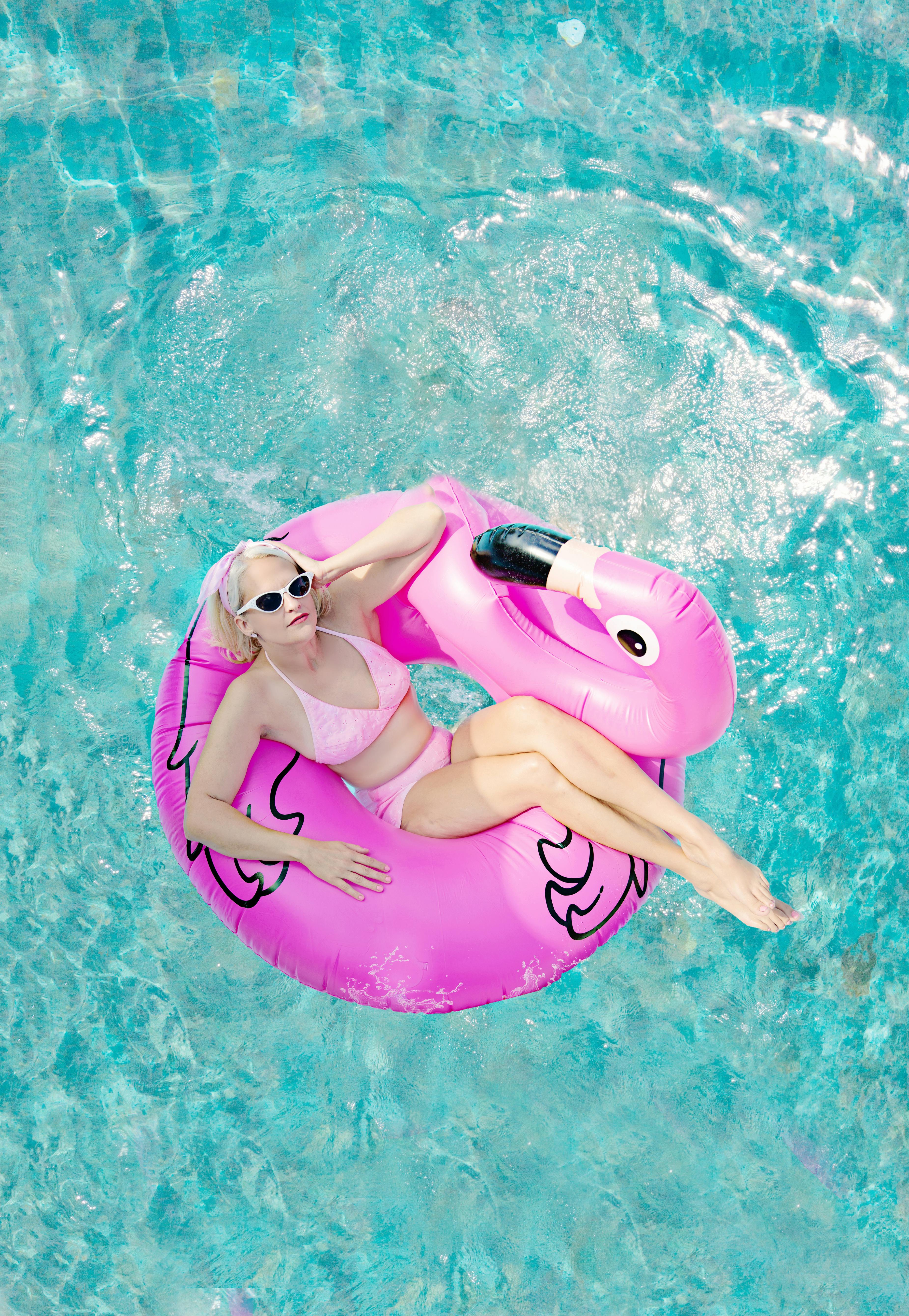 Woman with wet hair resting at the edge of a swimming pool
