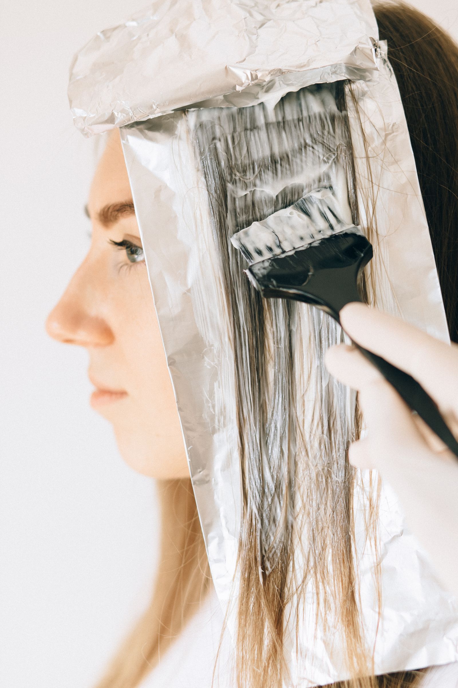 Close-up of foil highlights being applied with a color brush during a salon service