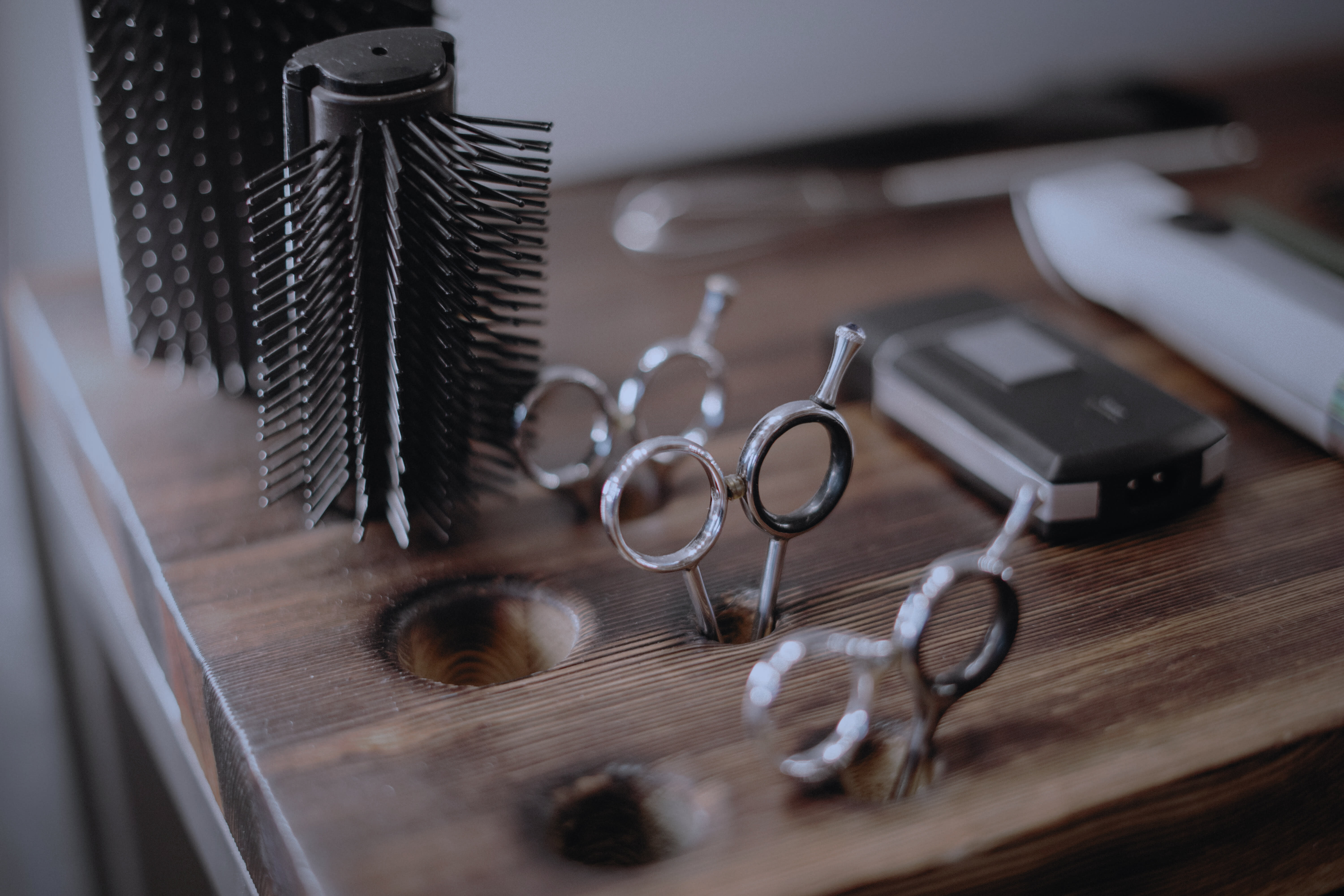 Barber's facial hair trimmer and hair clipper, accompanied by hairdresser's round black brush and multiple hair scissors.