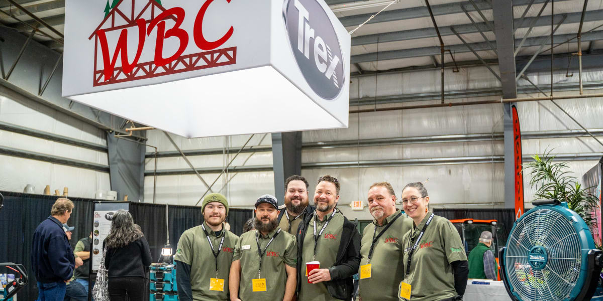 A team of seven Western Building Center employees poses together at their trade show booth at the 2025 Home and Garden Show