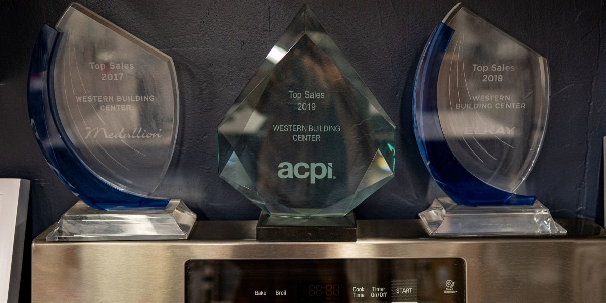 Three crystal awards displayed on what appears to be a microwave or appliance surface, recognizing Western Building Center's