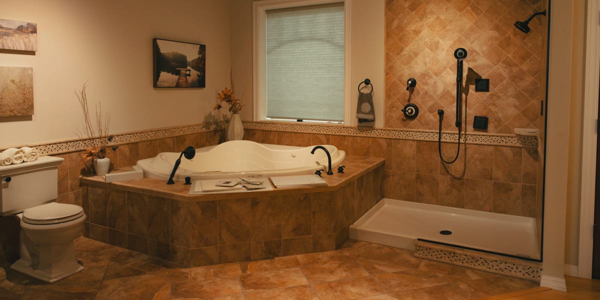An elegant residential bathroom featuring a corner jetted bathtub with tile surround, a glass-enclosed shower with multiple s