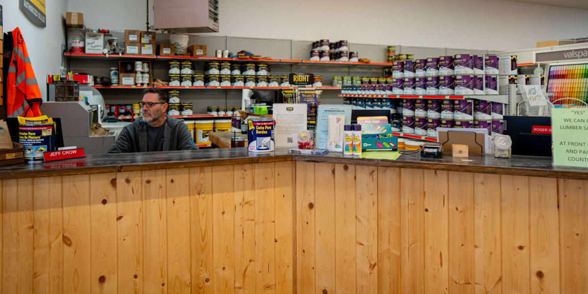 Interior view of a Western Building Center store showing the main service counter with wood paneling and a male employee with