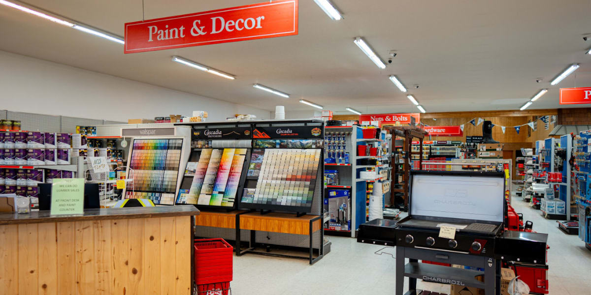 Interior view of the paint and decor department showing paint color displays with sample cards, paint mixing stations, and br