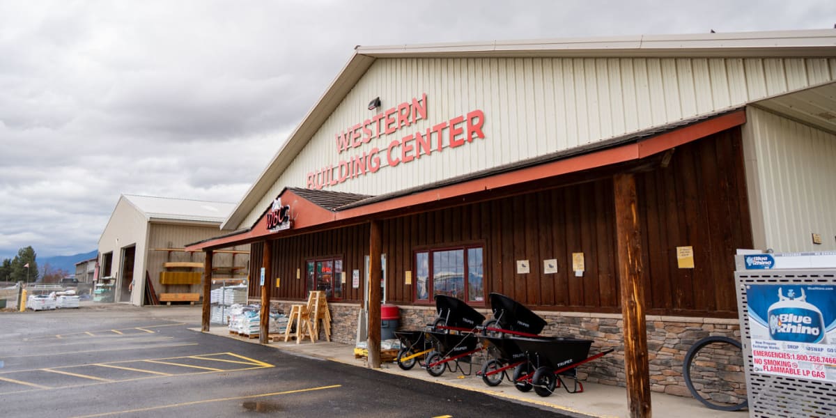 Exterior view of Western Building Center store featuring a warehouse-style building with cream-colored metal siding and wood