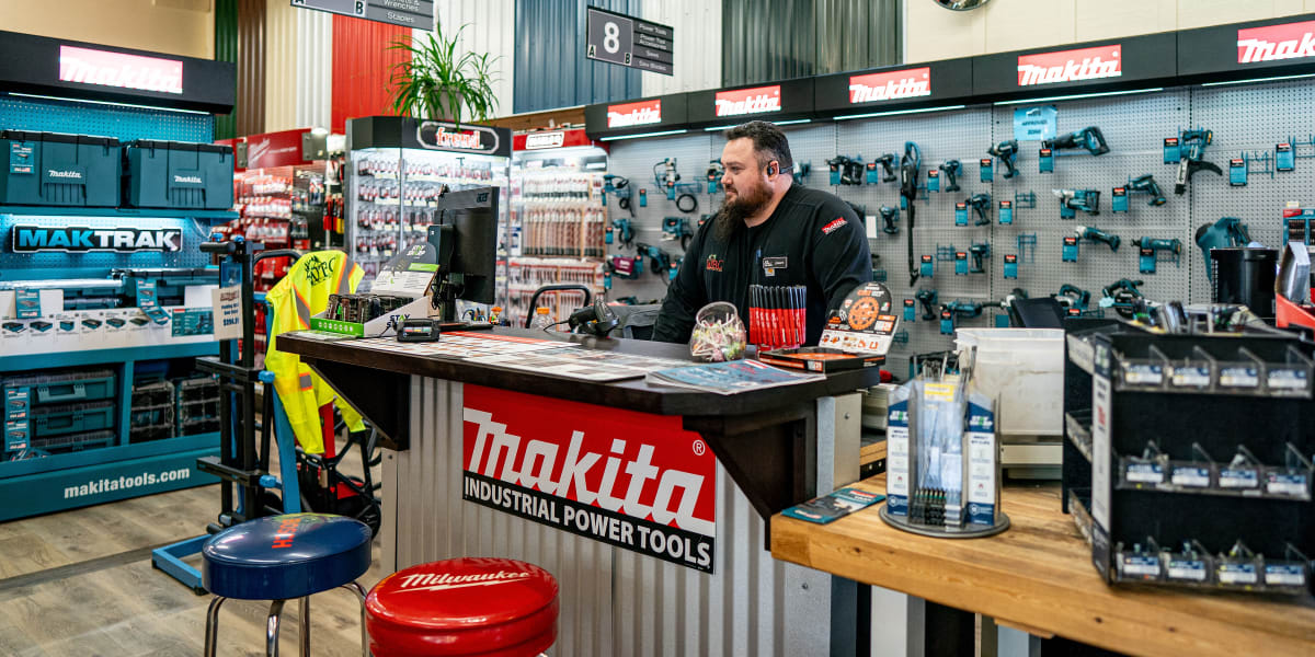Interior view of the tool department showing a Makita Industrial Power Tools counter with an employee working at a computer t
