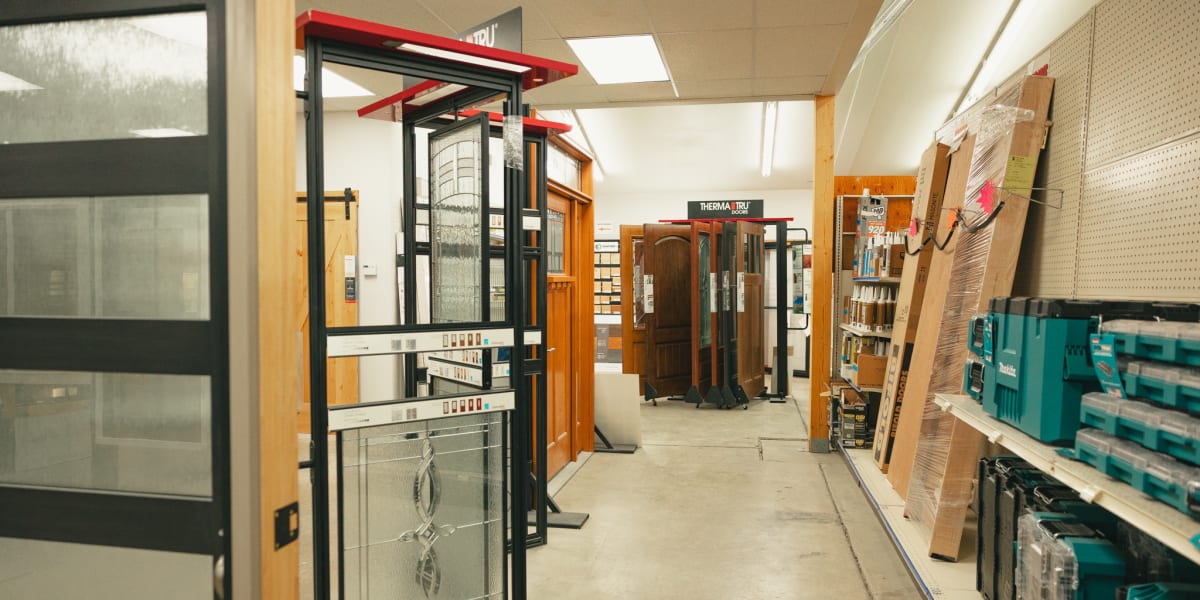 Interior view of a building supply store showroom displaying various door and window products