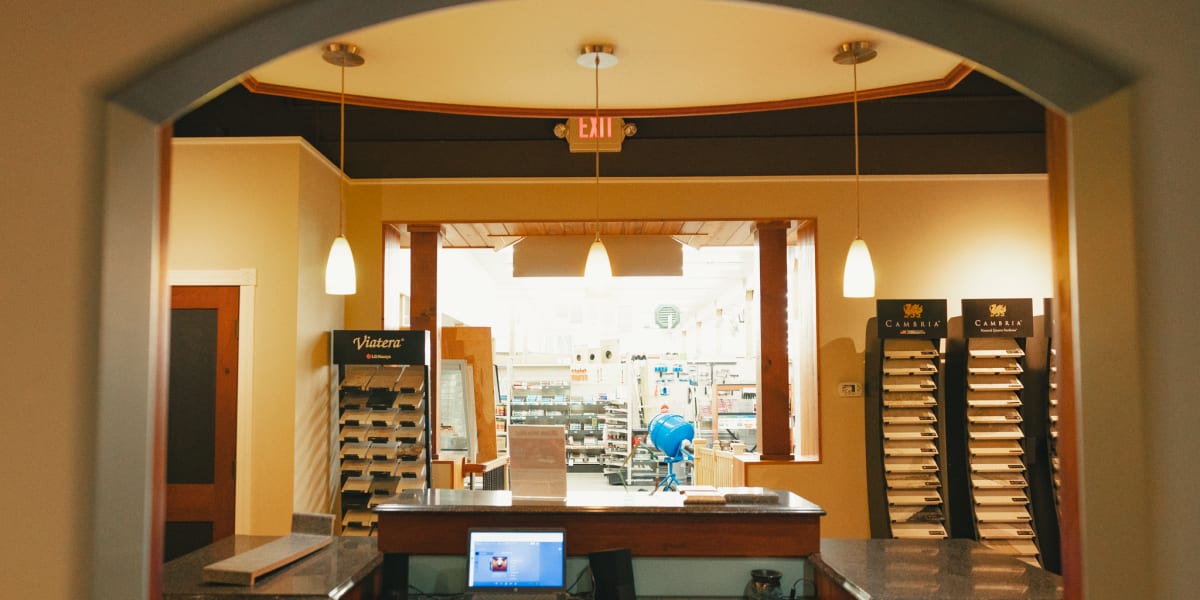 Interior view of a building supply showroom featuring a design center area with flooring samples and material displays